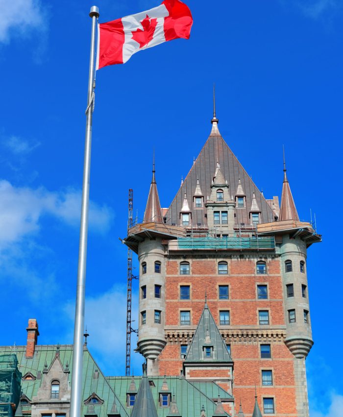 Chateau Frontenac in the day with cloud and blue sky in Quebec City with national flag